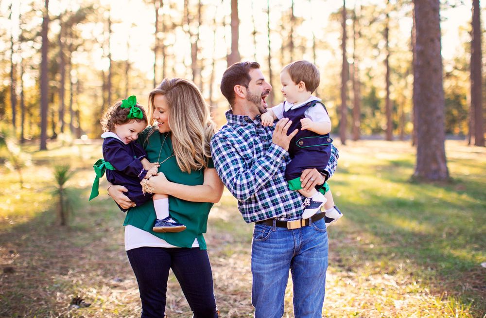 Family playtime in a sunlit forest setting during golden hour.