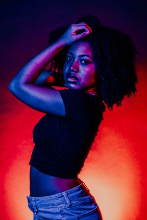 Stylized photoshoot with vibrant red backdrop and blue accent lighting creating depth.
