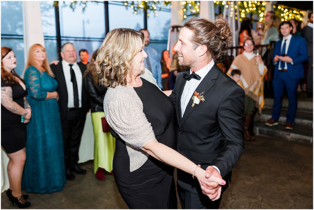 A couple shares their first dance at a wedding reception under twinkling lights.