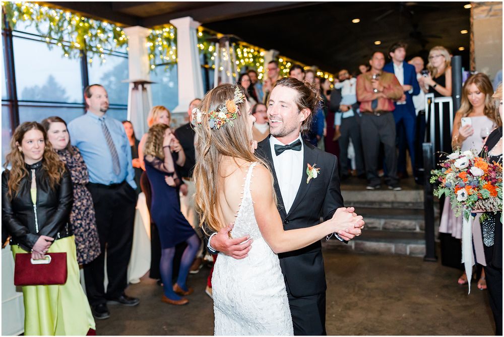 Couple dancing at their wedding reception while guests watch in background.