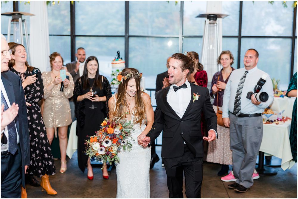 Wedding couple walking through venue with guests applauding during reception.