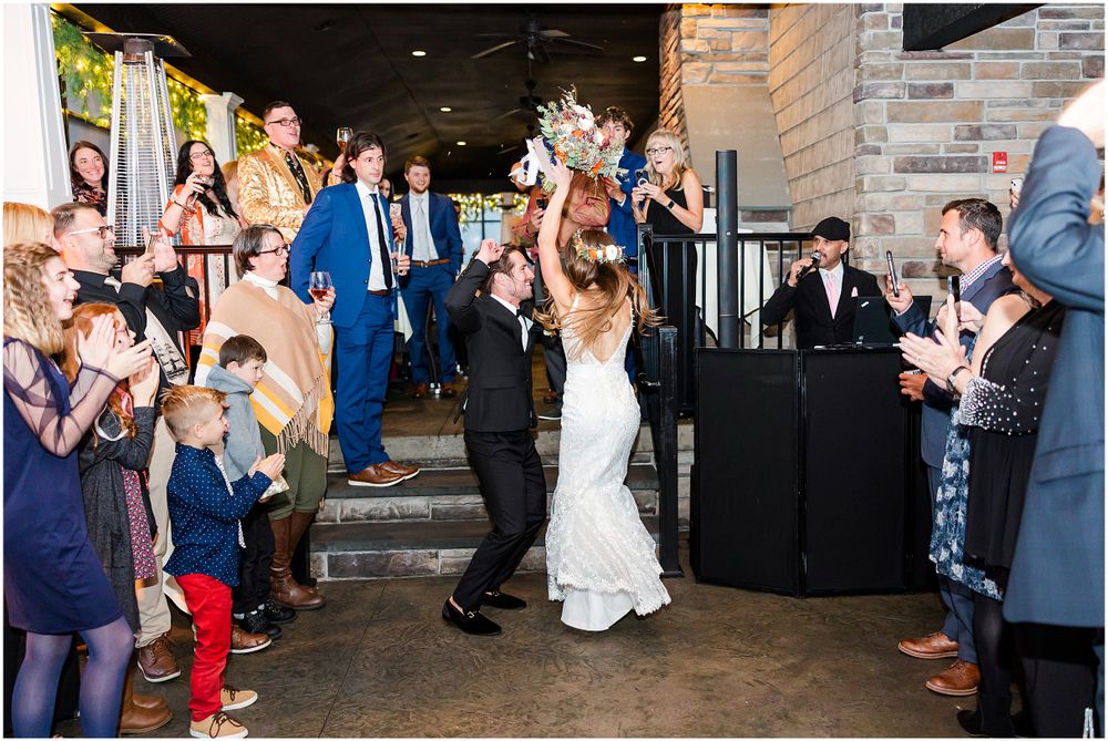 Wedding couple exiting venue while guests line walkway and celebrate.