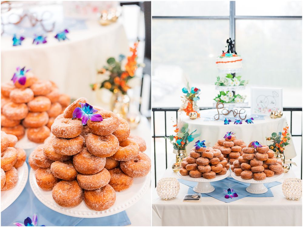 A wedding dessert display featuring tiers of glazed donuts and a white wedding cake decorated with blue flowers.