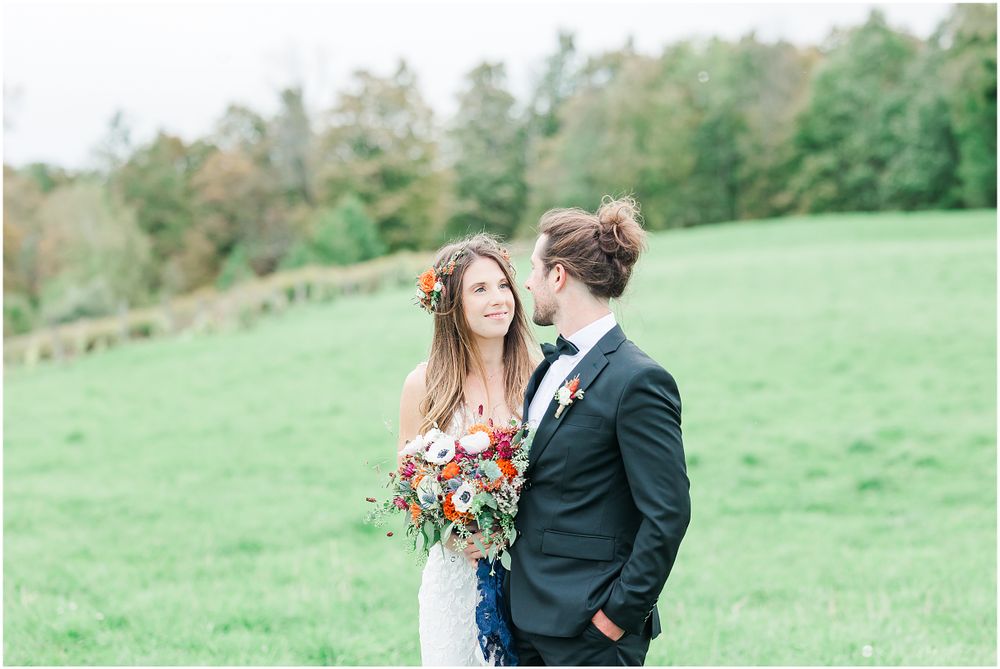 A couple shares a romantic moment in a green meadow during their wedding photoshoot.