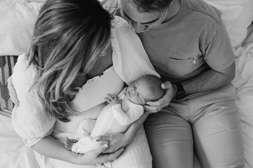Black and white photo of parents gazing lovingly at their newborn.