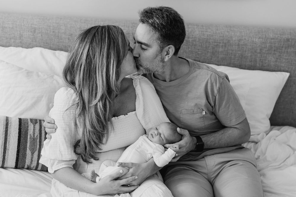 Black and white photo of couple sharing an intimate moment while sitting on bed.