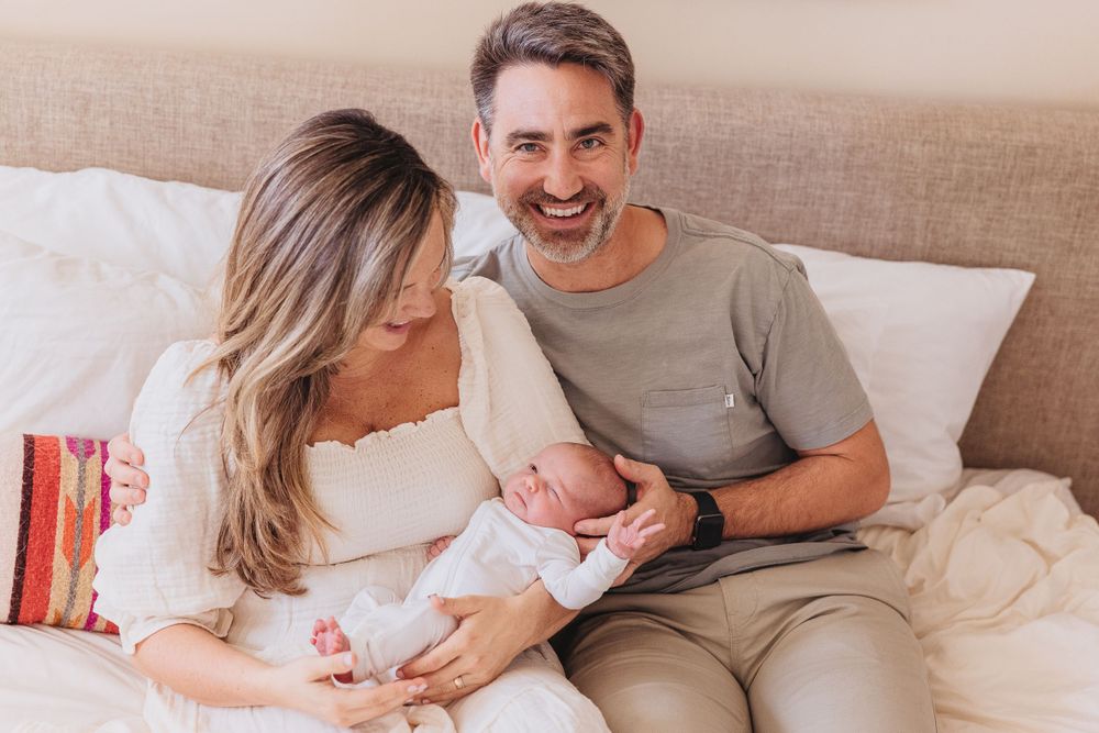 Family sharing a tender moment while sitting on their bed.