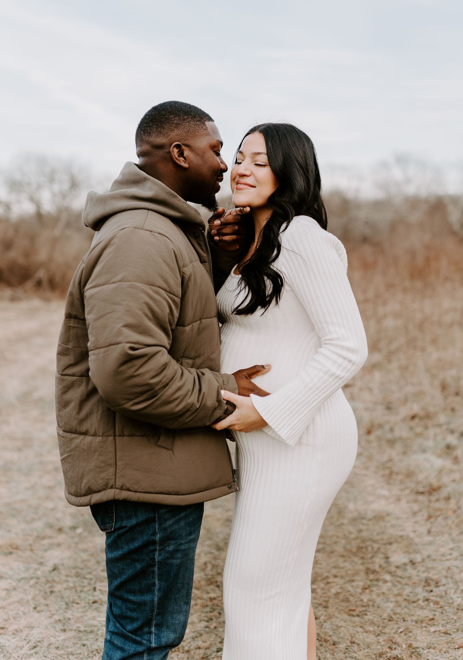 A couple laughs together during an outdoor photoshoot in a natural setting.