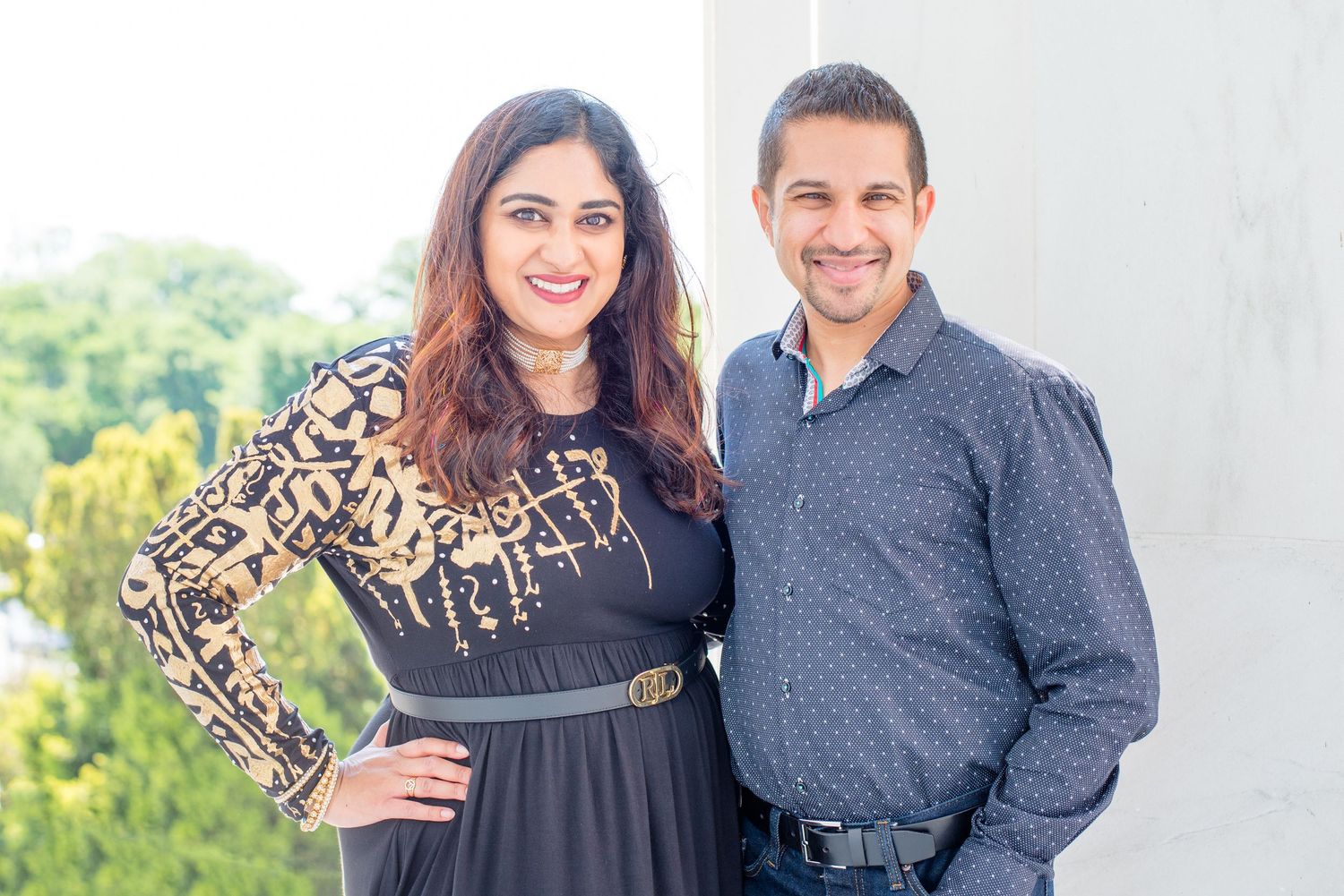husband and wife look at camera near a column, outside