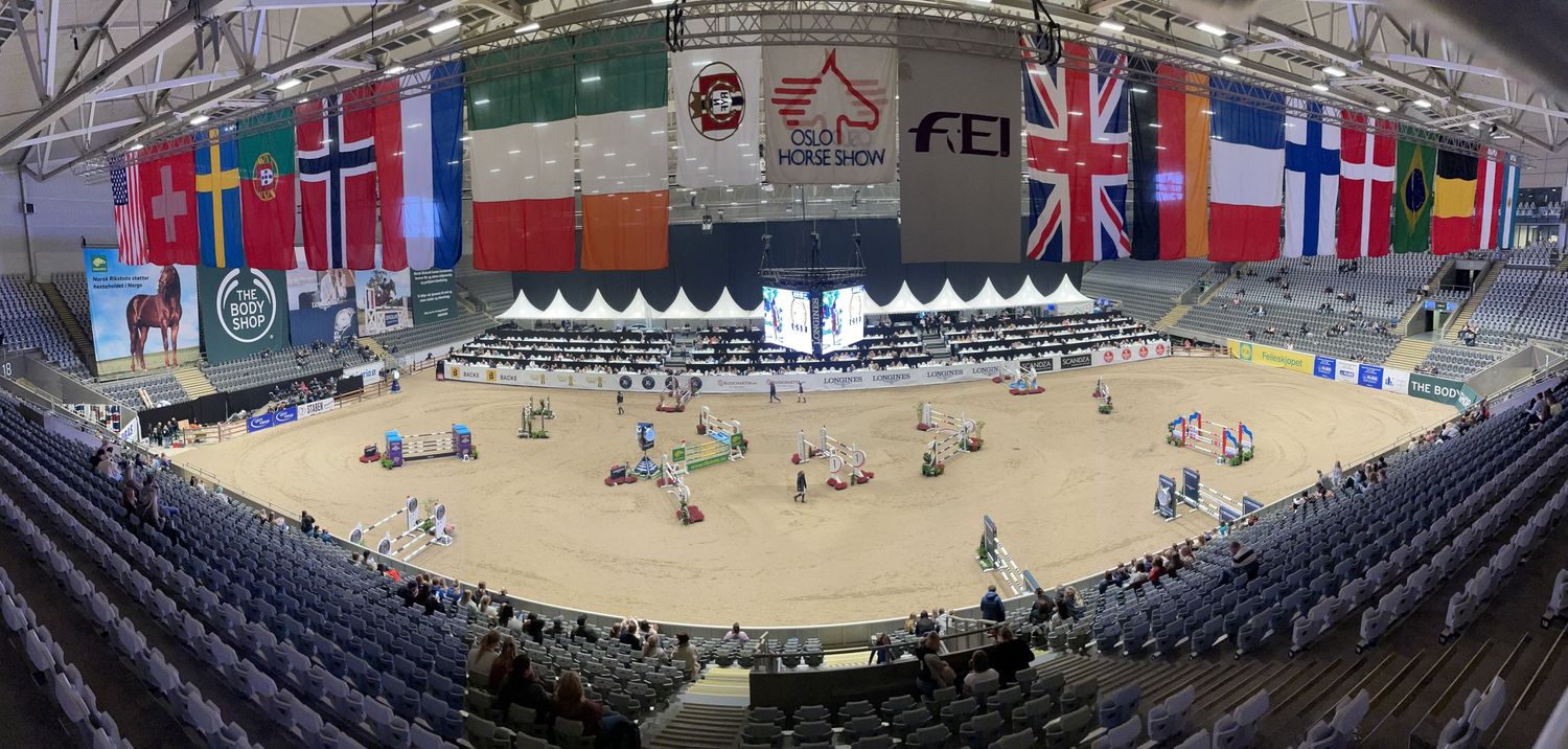 Equestrian arena with international flags displaying during an indoor competition event.
