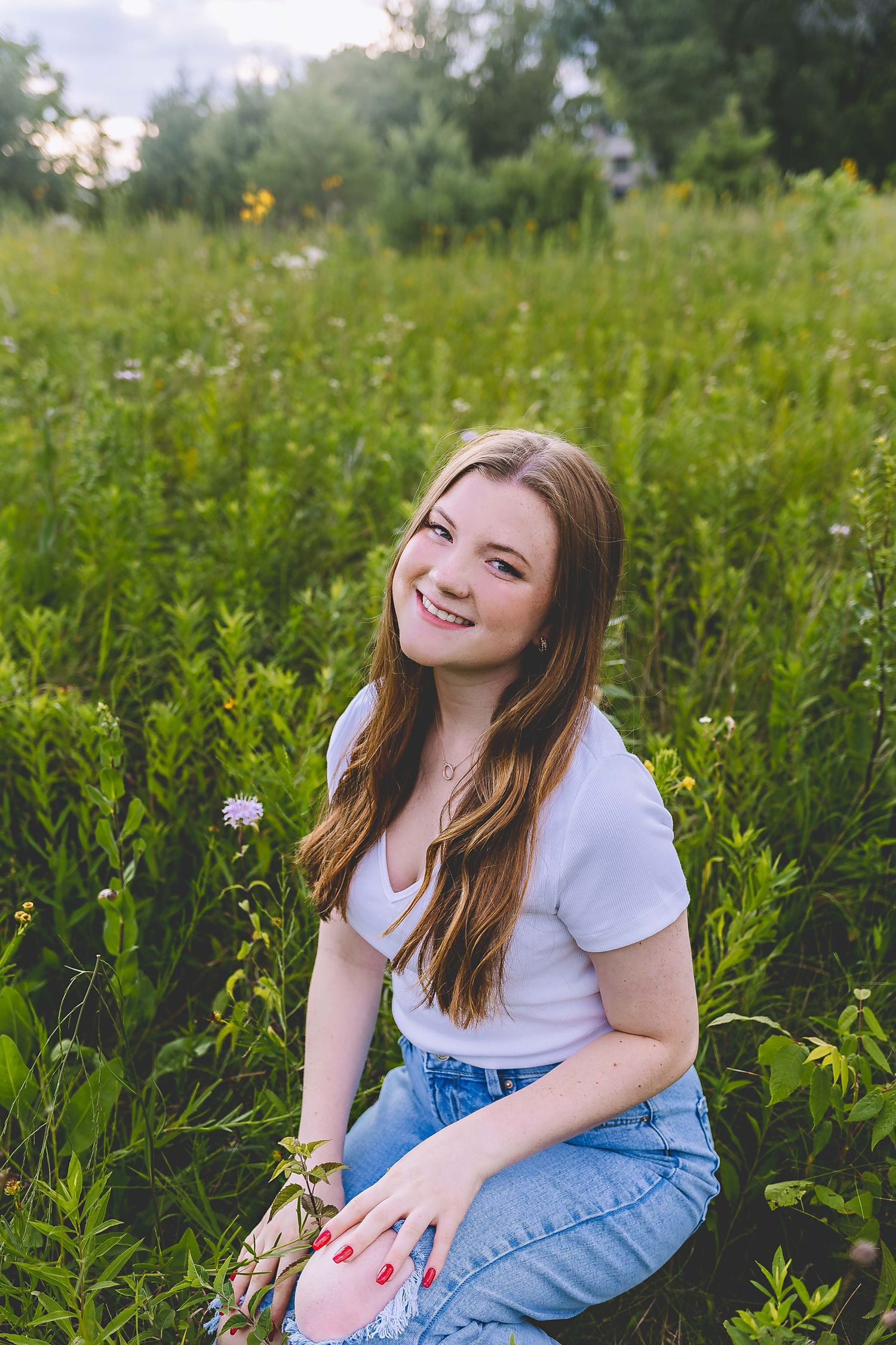 senior photo in field of flowers getting her senior photos down by photographer who works in lake country area