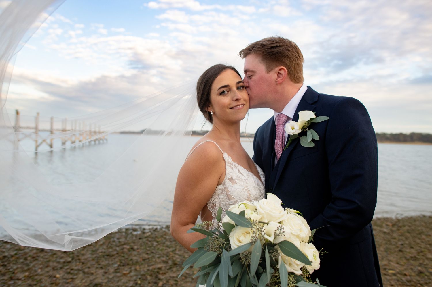 Romantic beach wedding portraits with ocean and power lines in background.