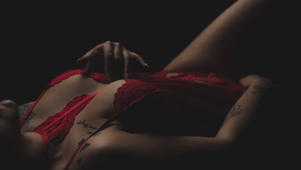 Artistic composition showing dark silhouette with red fabric accent in moody lighting.