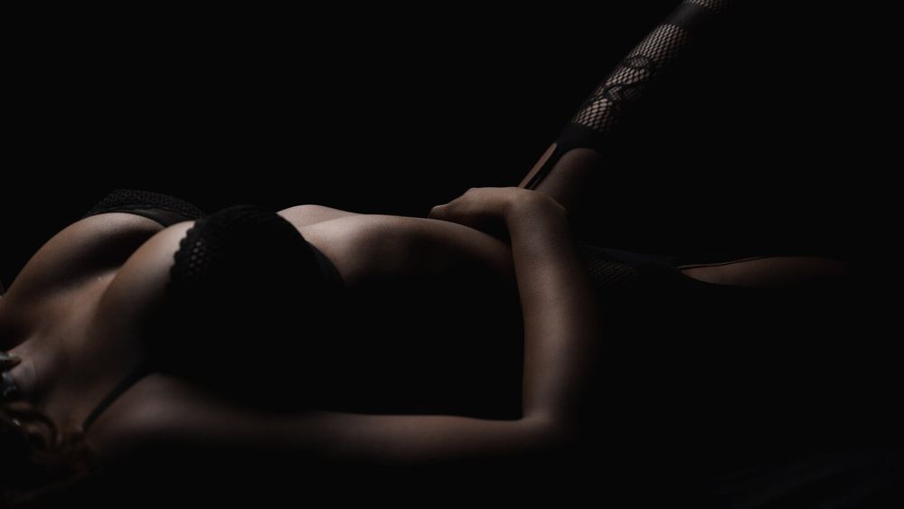 Minimalist black and white photograph highlighting curves and shadows in artistic nude study.