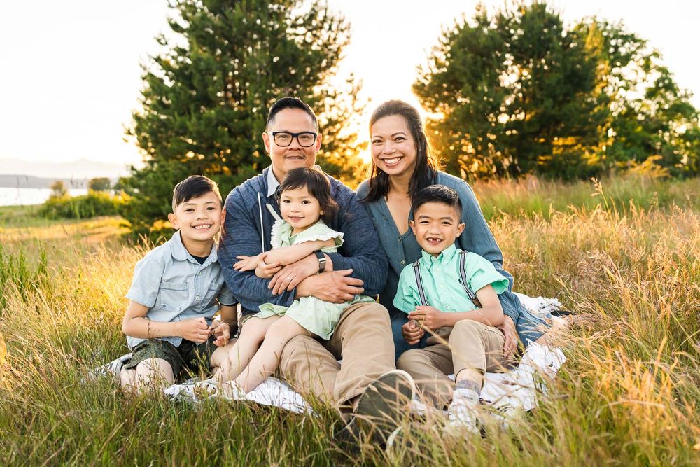 Golden hour family portrait in a grassy field with trees