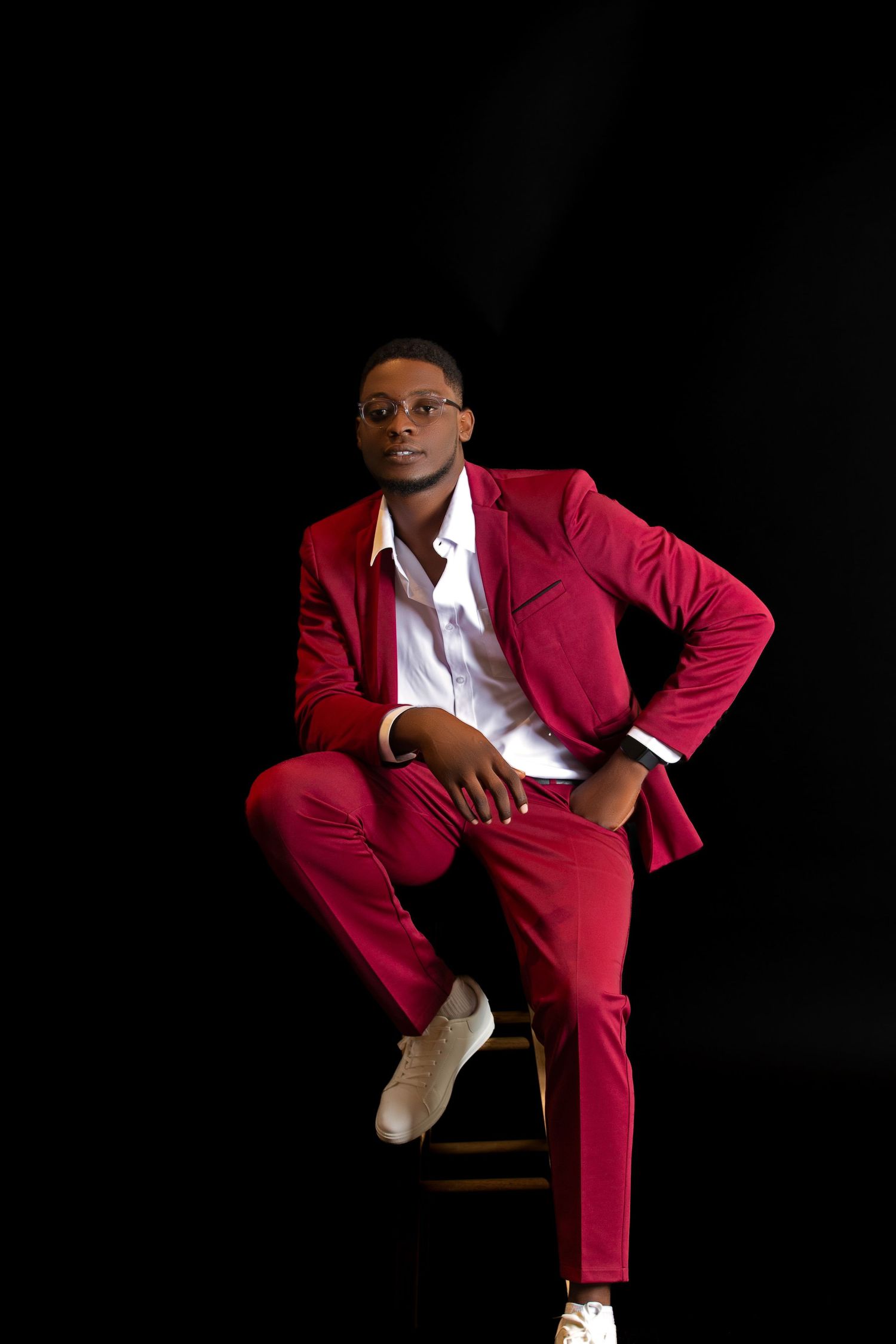 Stylish red suit portrait against black background.