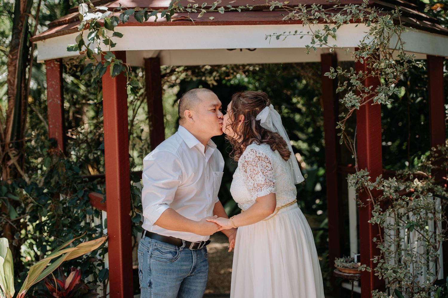Romantic moment between newlyweds under garden gazebo during wedding ceremony.
