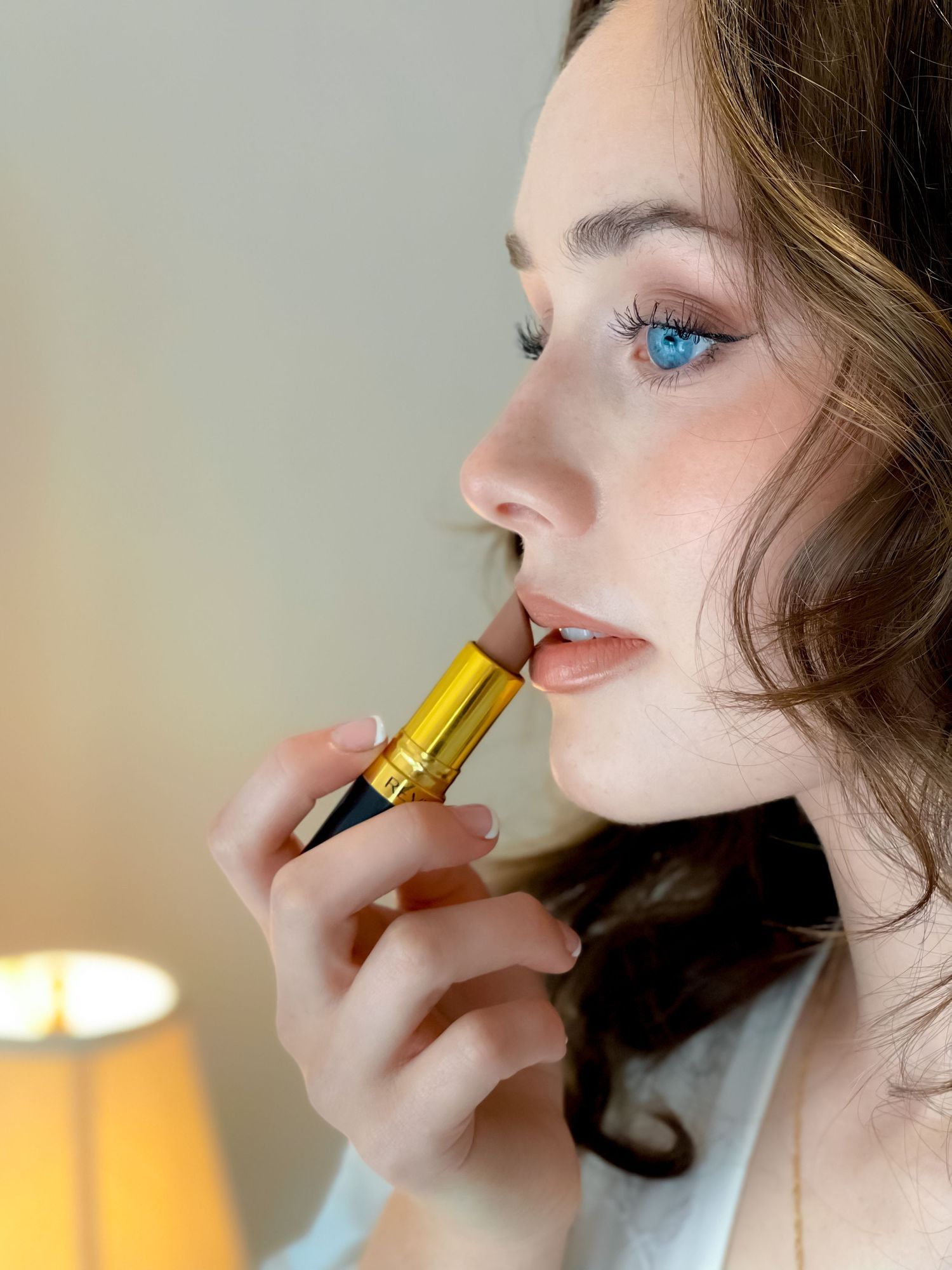A close-up beauty shot shows the application of golden lipstick.