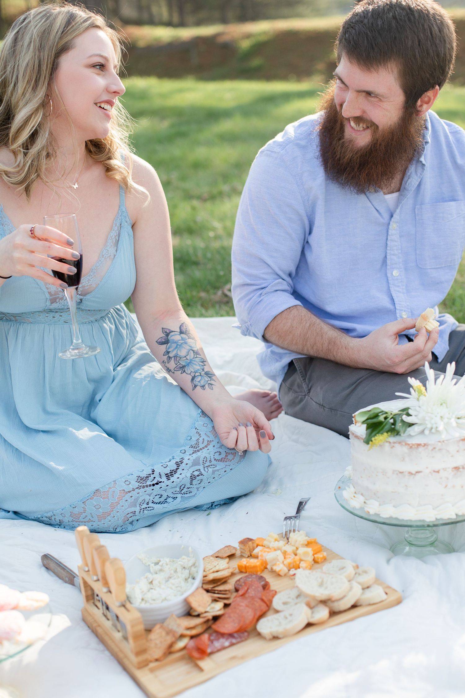 Couple enjoying wine and charcuterie at a romantic outdoor picnic.