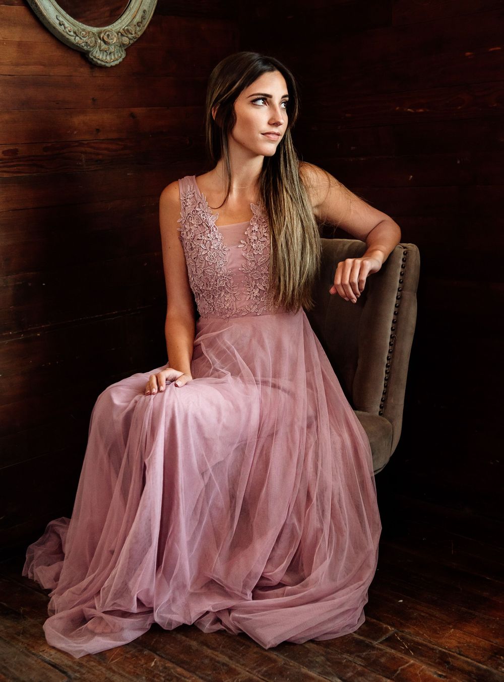 Elegant mauve gown with lace details photographed in rustic setting with wooden walls.