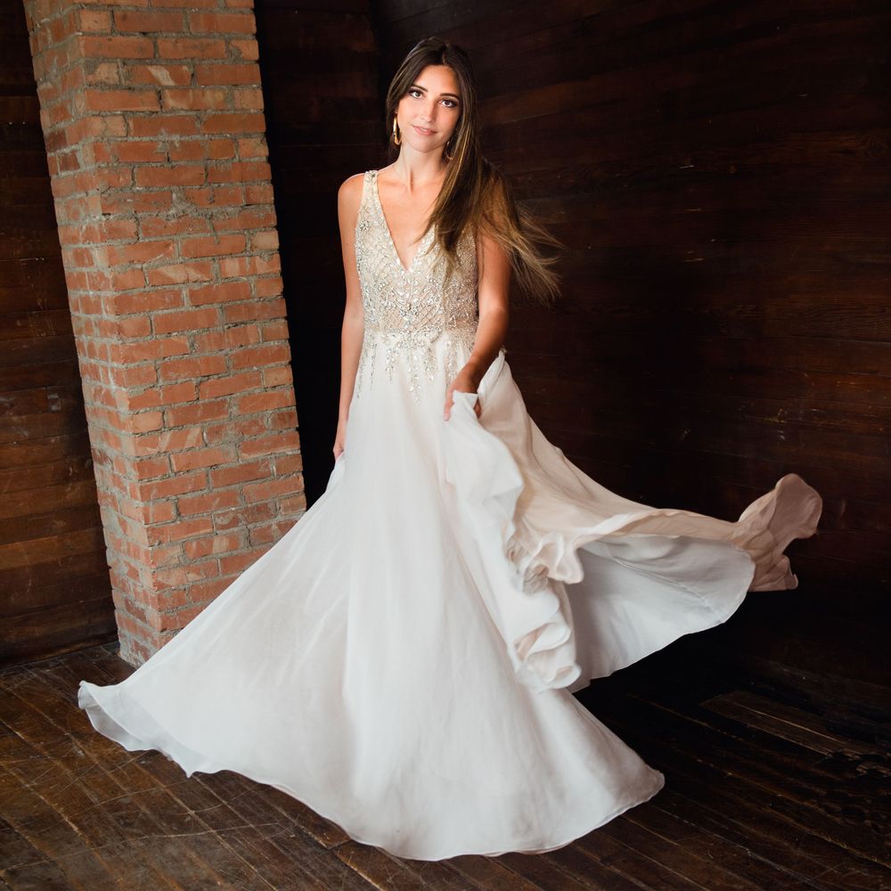 Flowing white wedding gown with lace bodice twirling in rustic brick venue.