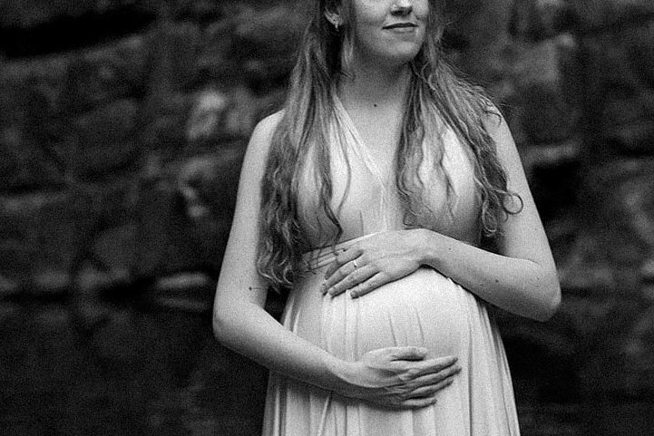 Nikeesha, mother, cradling her pregnant belly with hair flowing down her chest