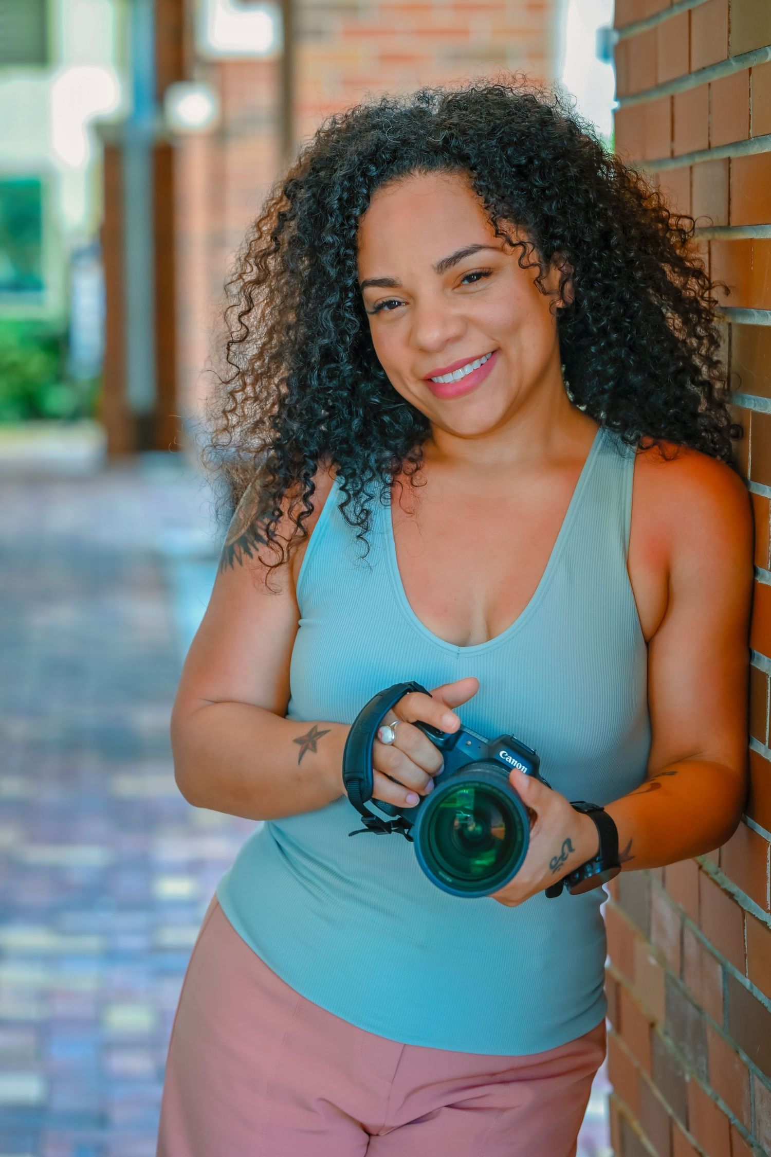 Photographer in casual attire takes professional headshots against brick wall.