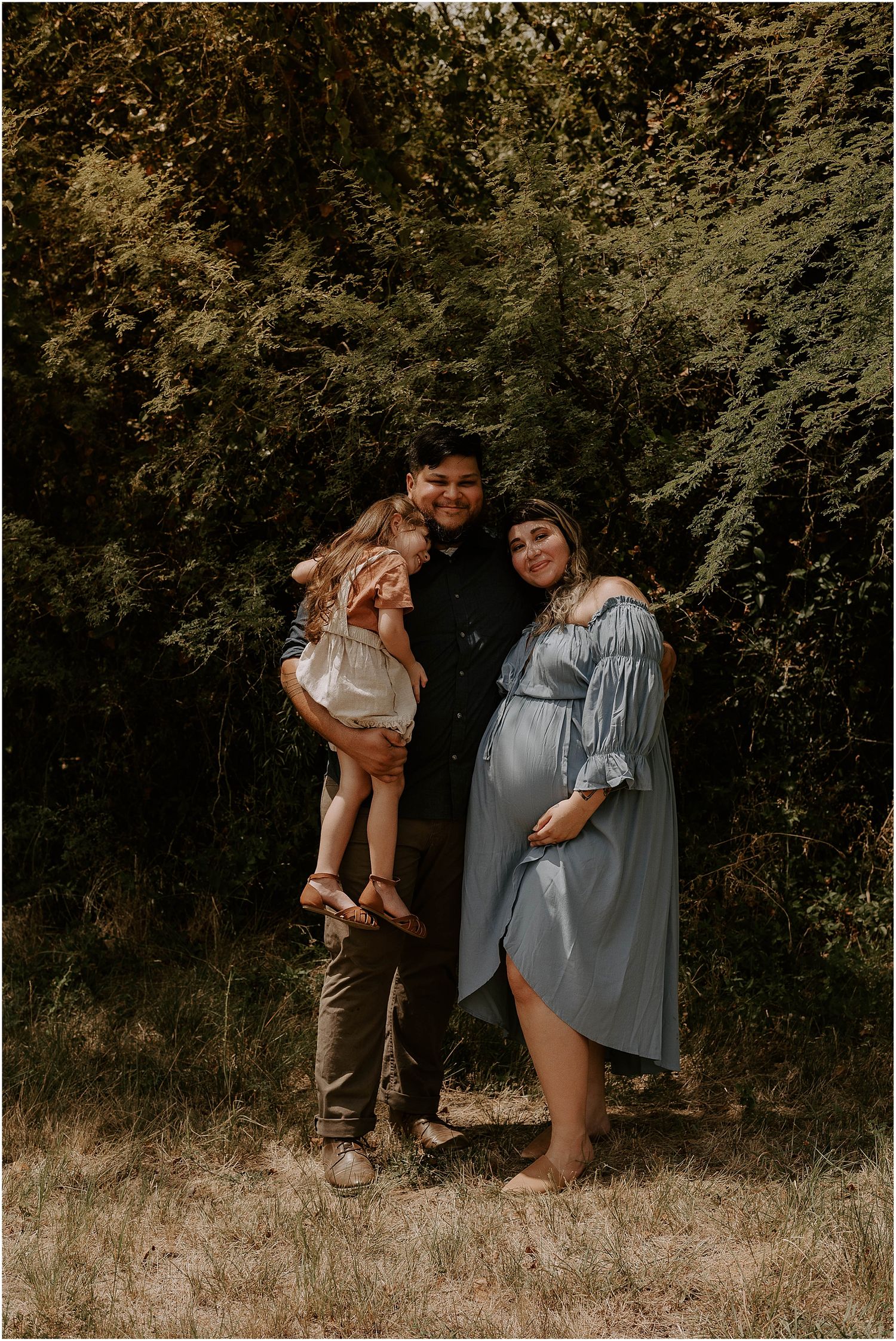 Family maternity portrait in woodland setting with toddler and blue dress.