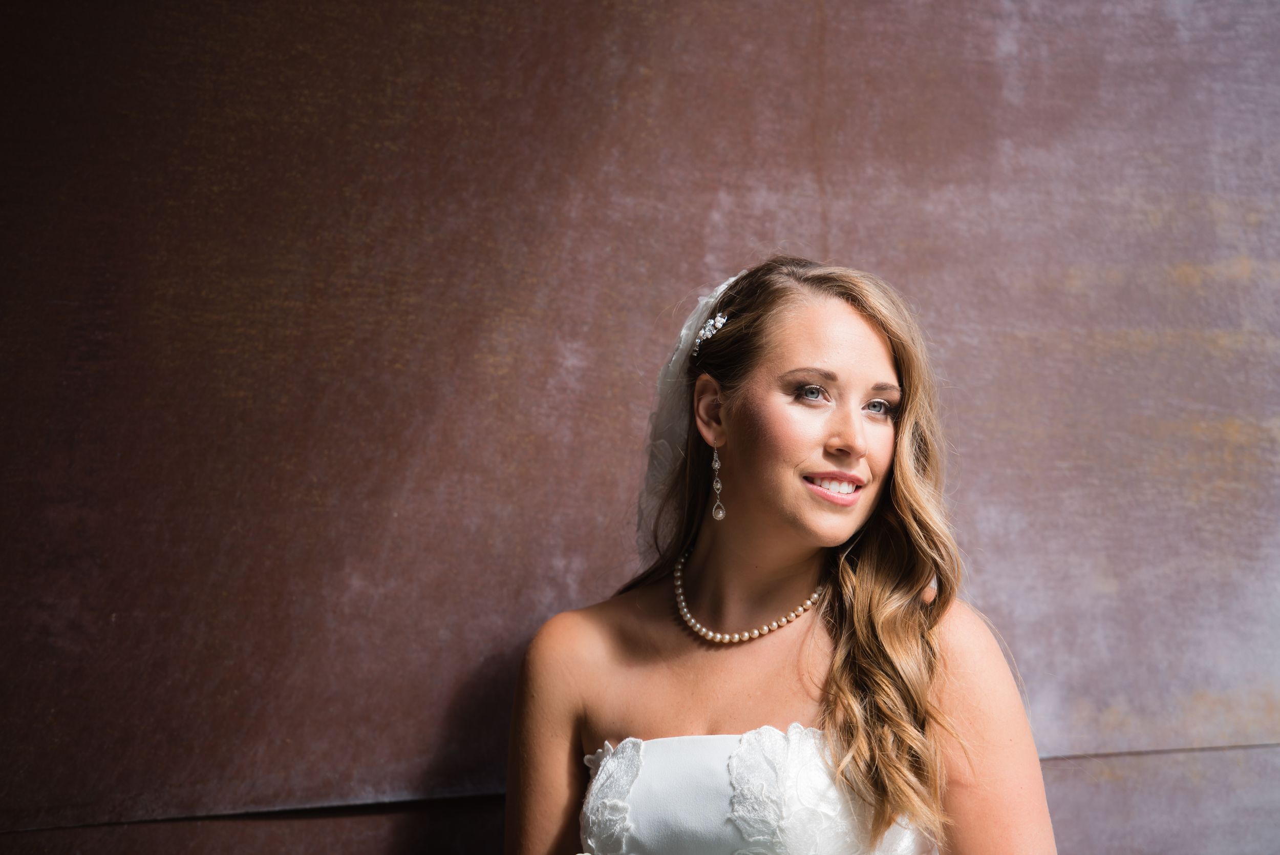Elegant bridal portraits against a dark wooden wall background.