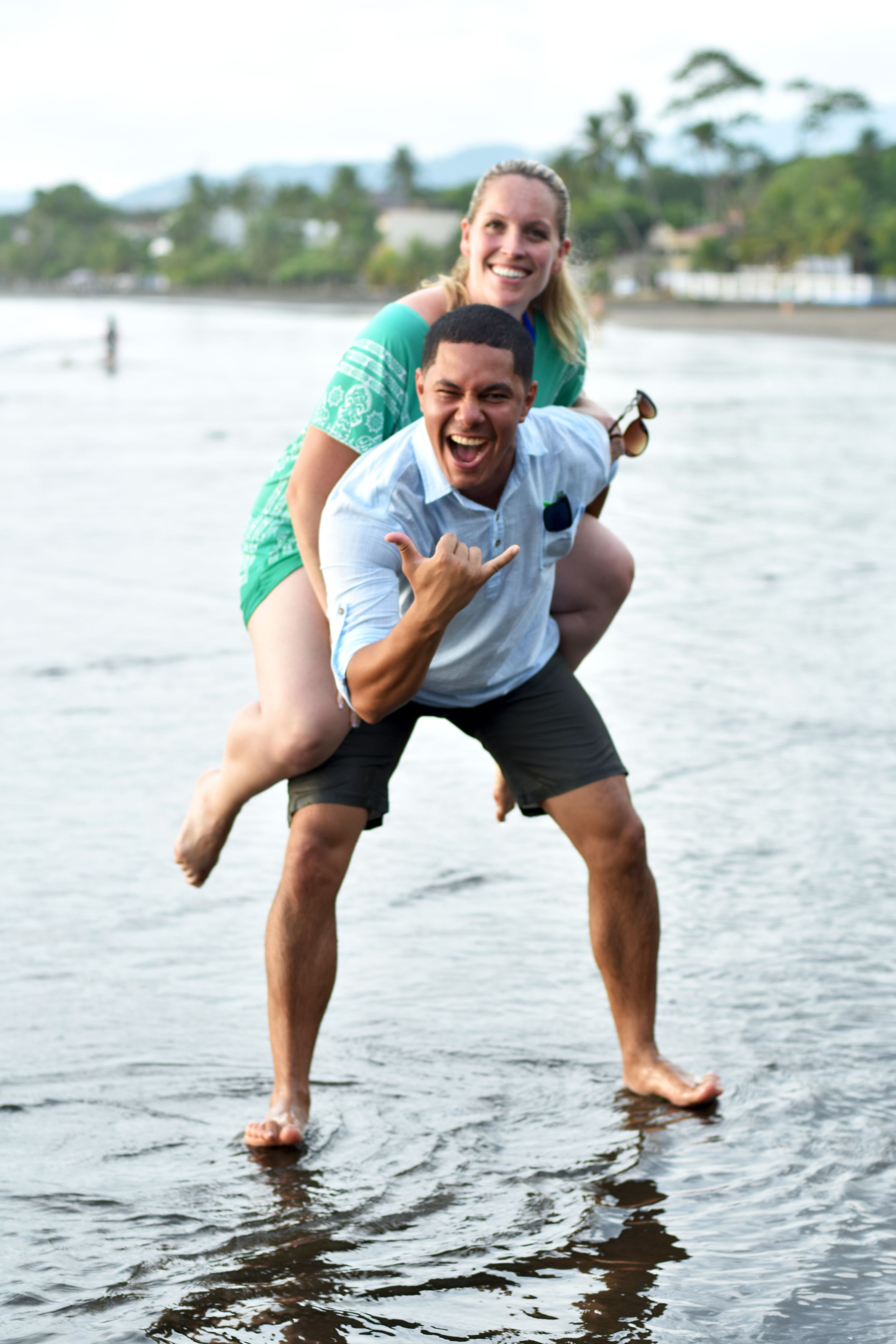 Woman on fiancé's back on the beach