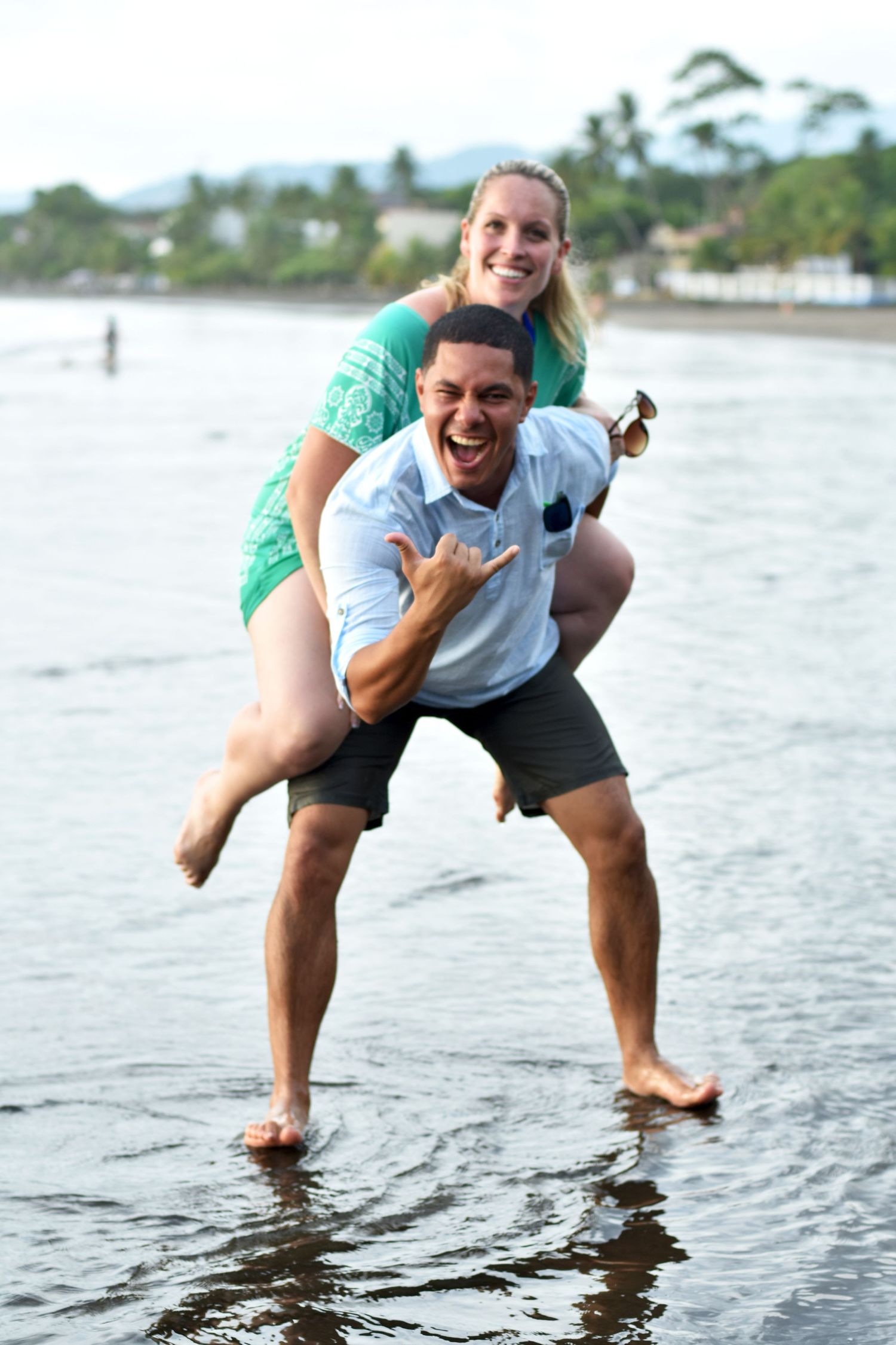 Woman on fiancé's back on the beach