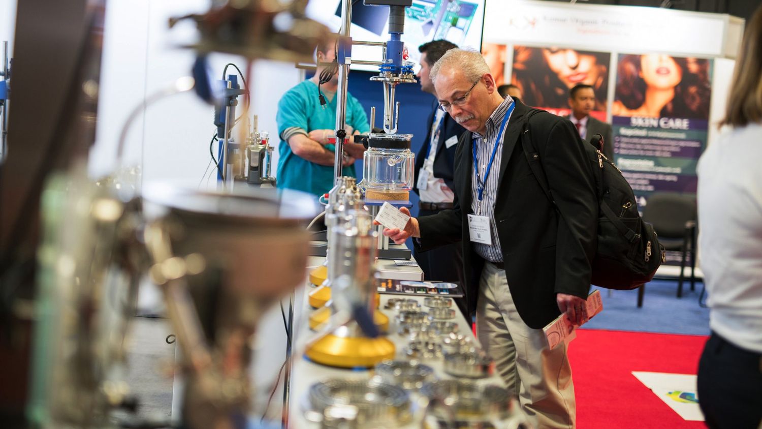 Trade show attendees examining scientific equipment at exhibition booth.