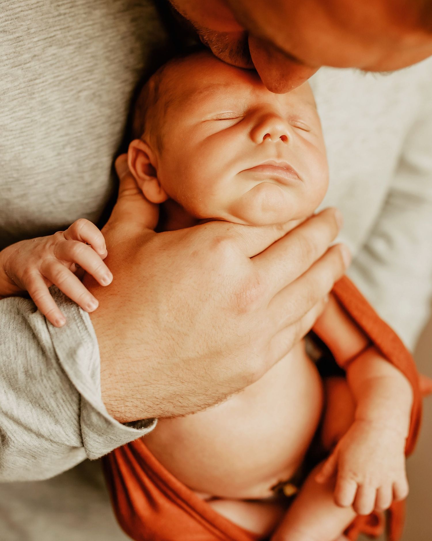 Close-up portrait of newborn baby with gentle hands providing comfort.