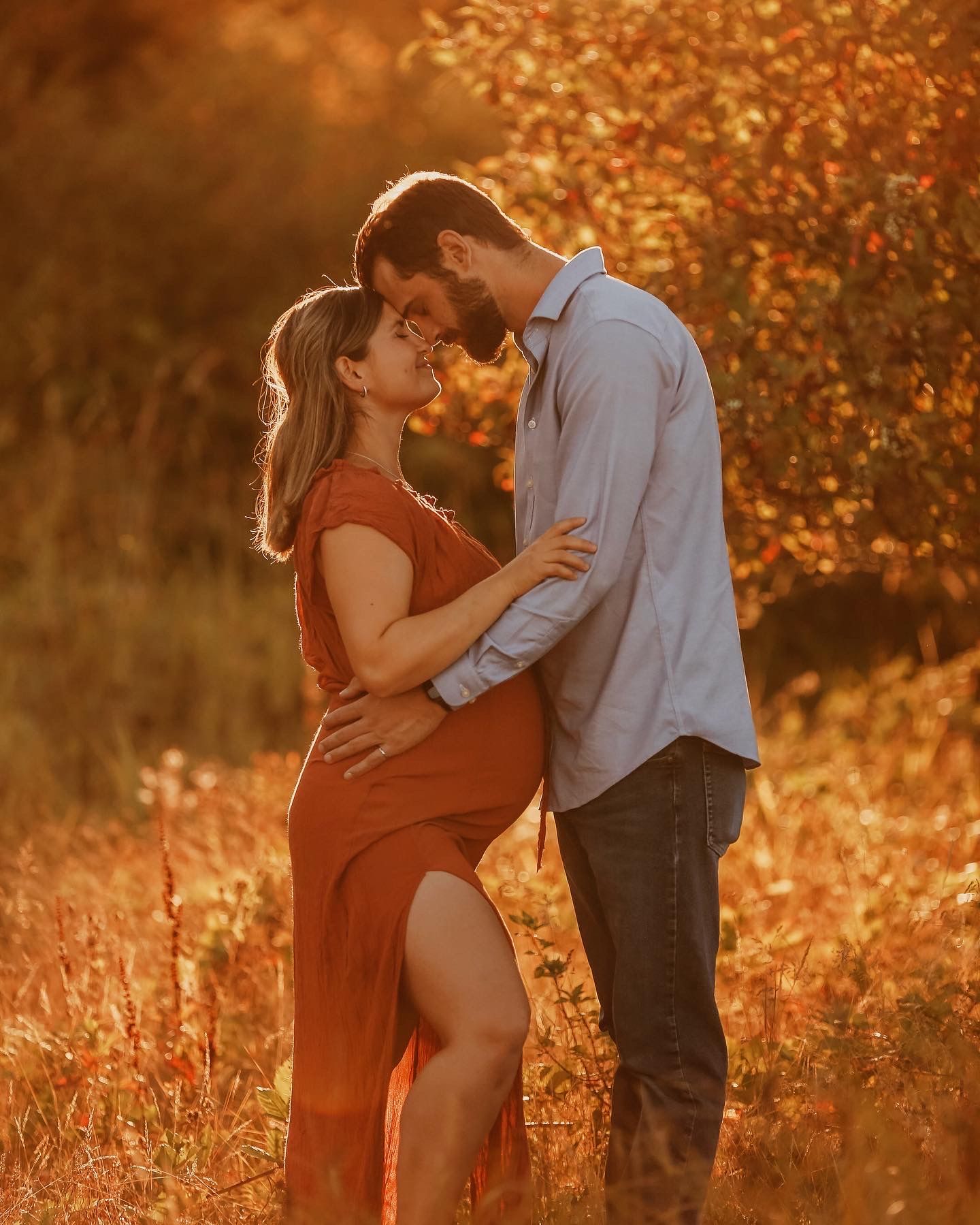 A couple embraces in a romantic sunset photoshoot with golden autumn foliage glowing in the background.