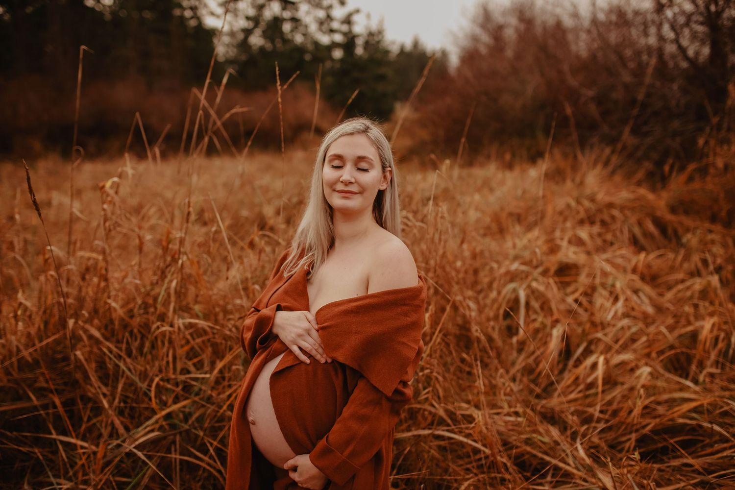 Woman in red dress poses in golden autumn field during sunset portrait session.