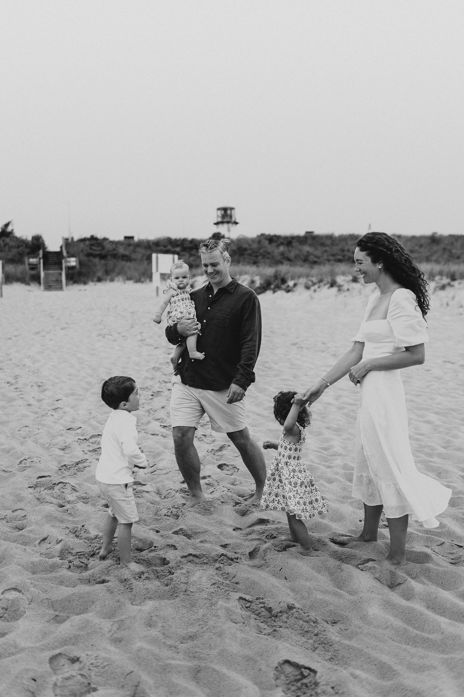 Family playing together on sandy beach in black and white photography.