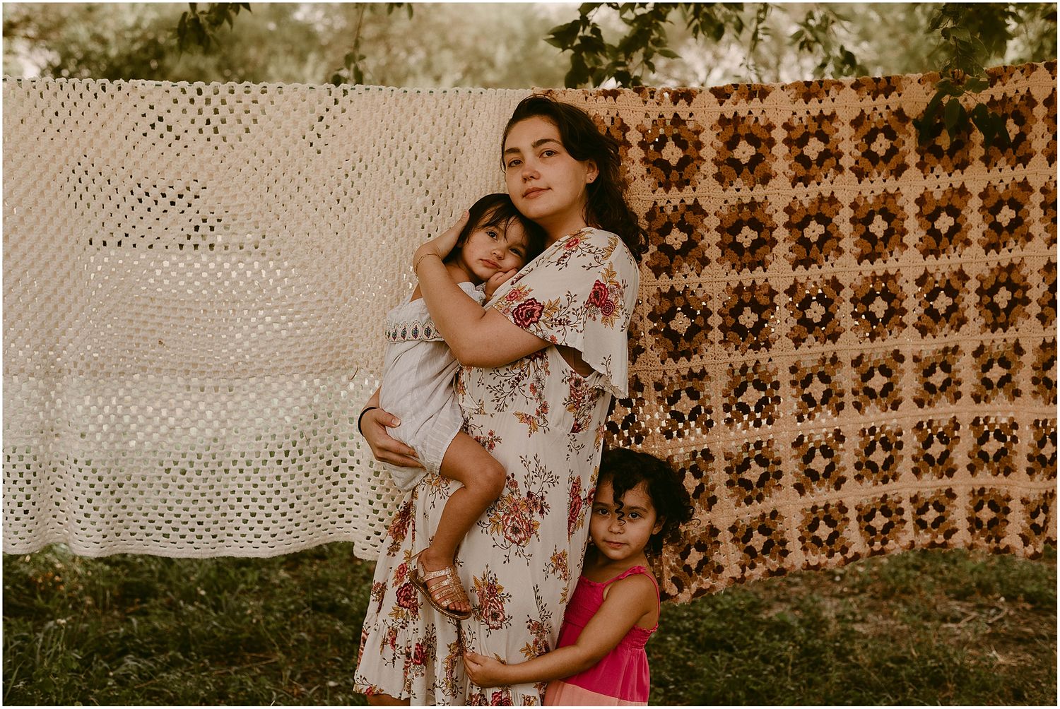 An intimate family portrait against a backdrop of white lace and brown floral patterns.