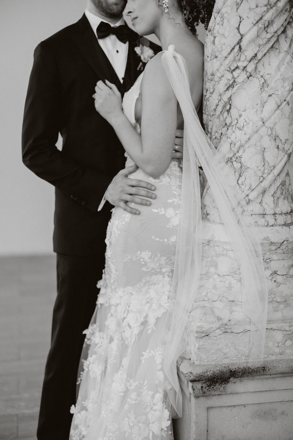 A groom with his hands around his bride's waist to highlight their wedding day attire at Ringling Museum in Sarasota.