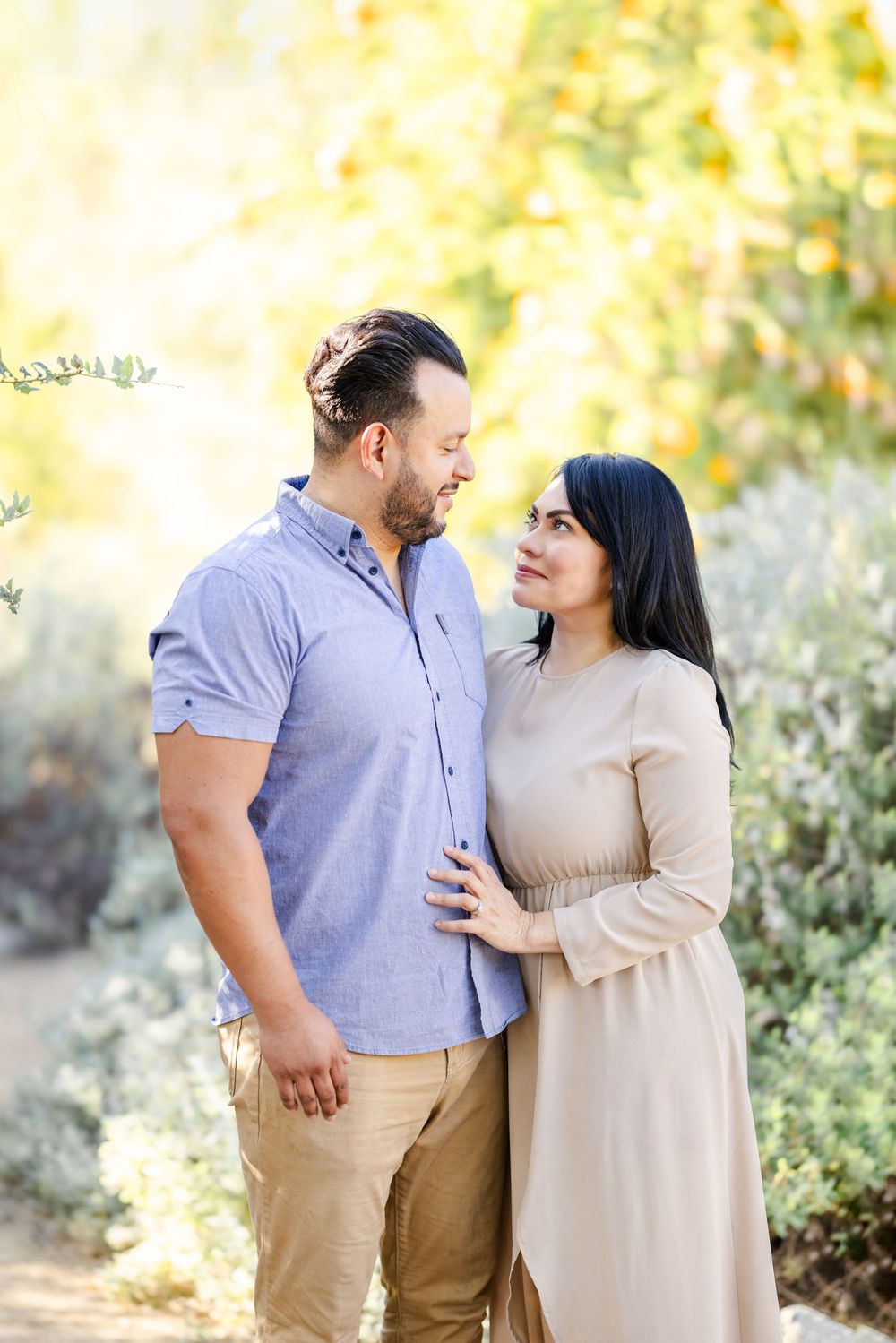 Couple shares tender moments in casual attire against a bright natural backdrop.