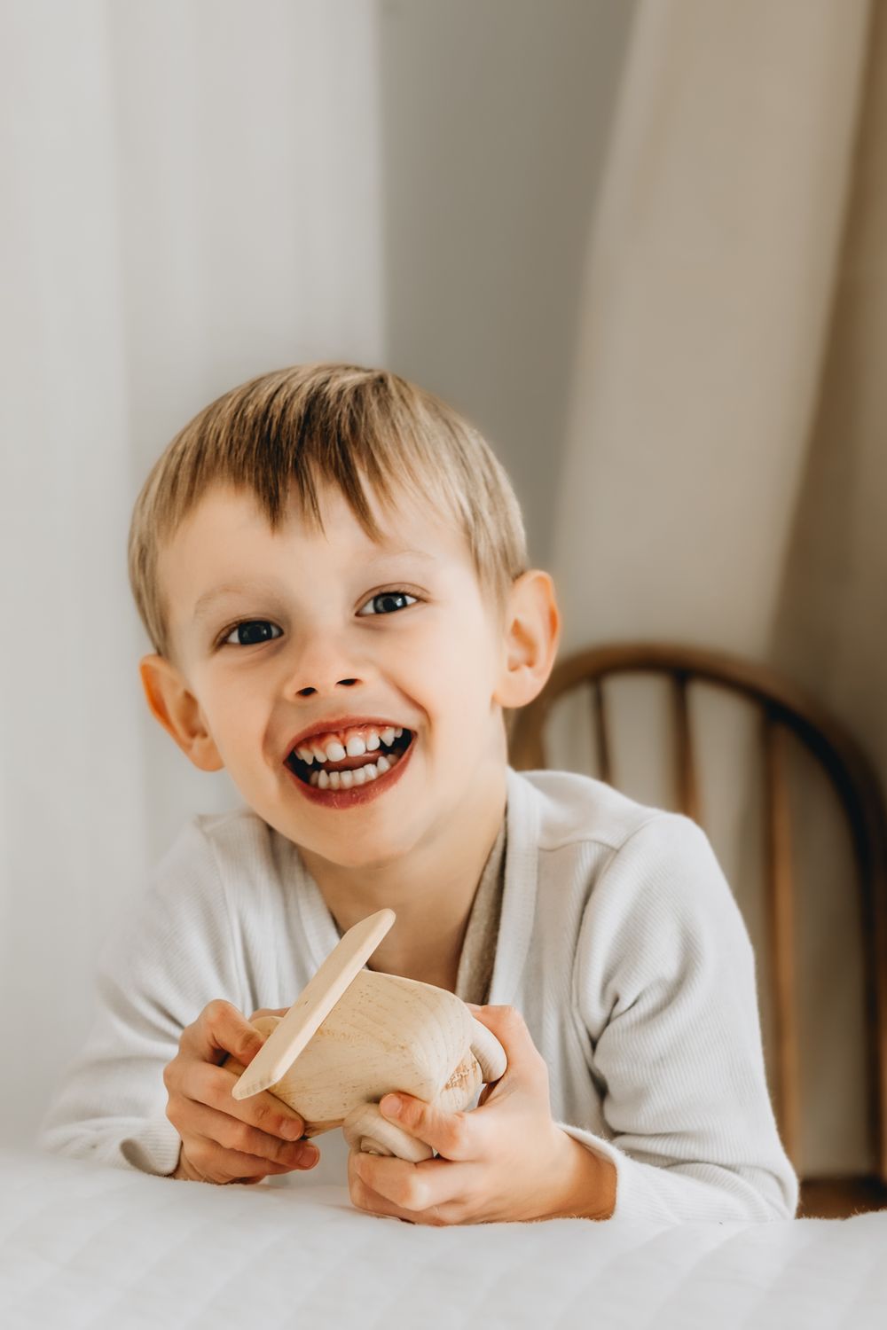 Cheerful child enjoying a snack while sitting at white table.