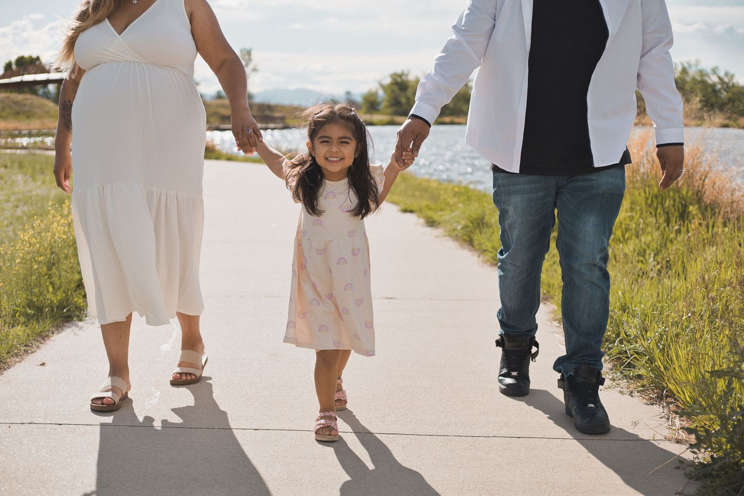 toddler holding hands with parents family maternity portrait by lake