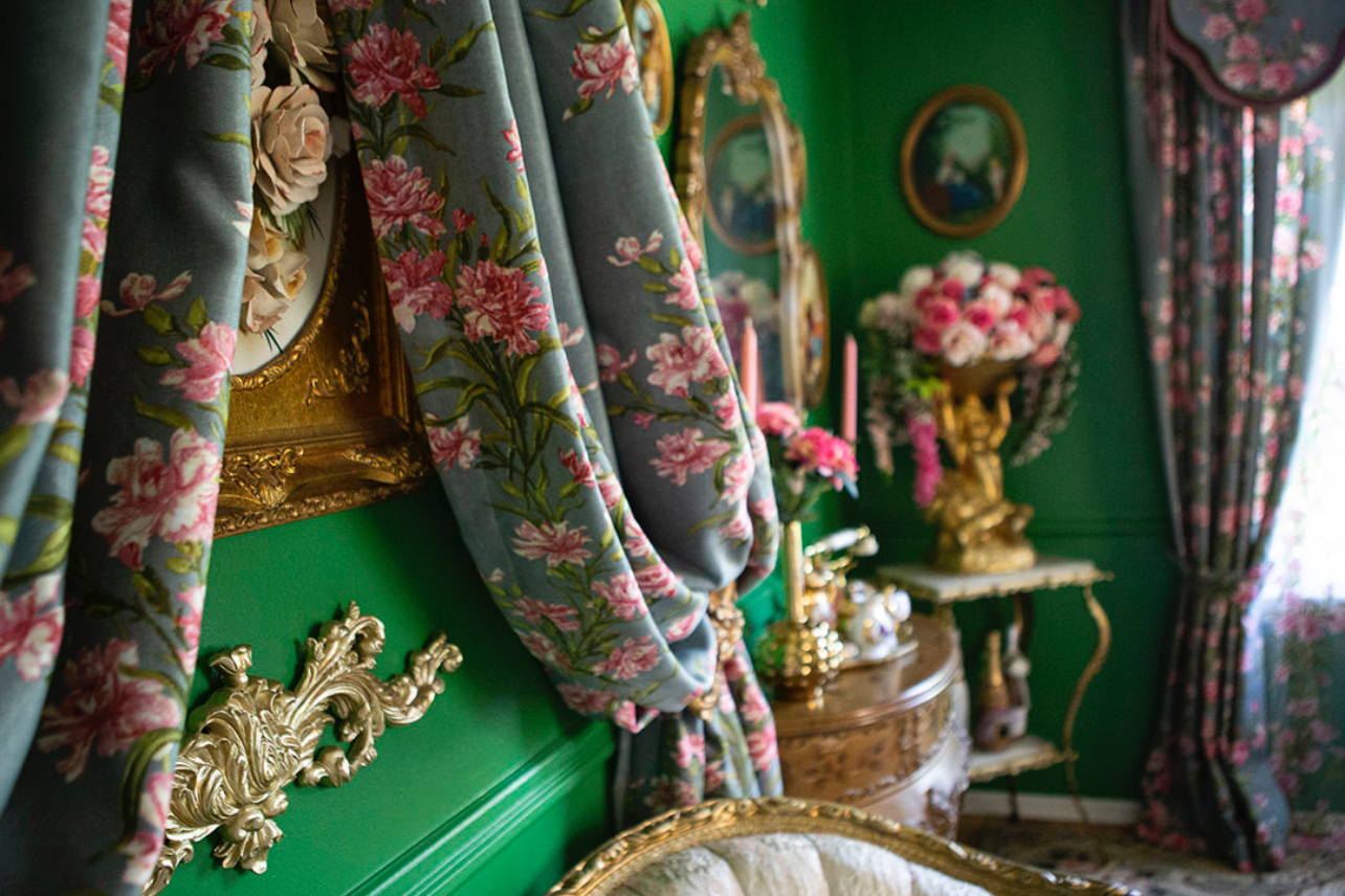 Ornate Victorian interior with floral curtains and gold accents against emerald green walls.