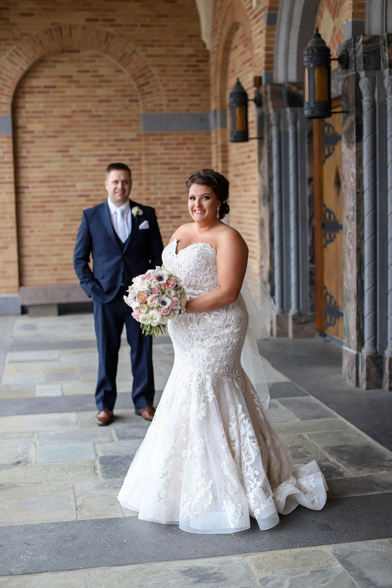 Bride in focus with groom in background in front of church, Minnesota wedding photography
