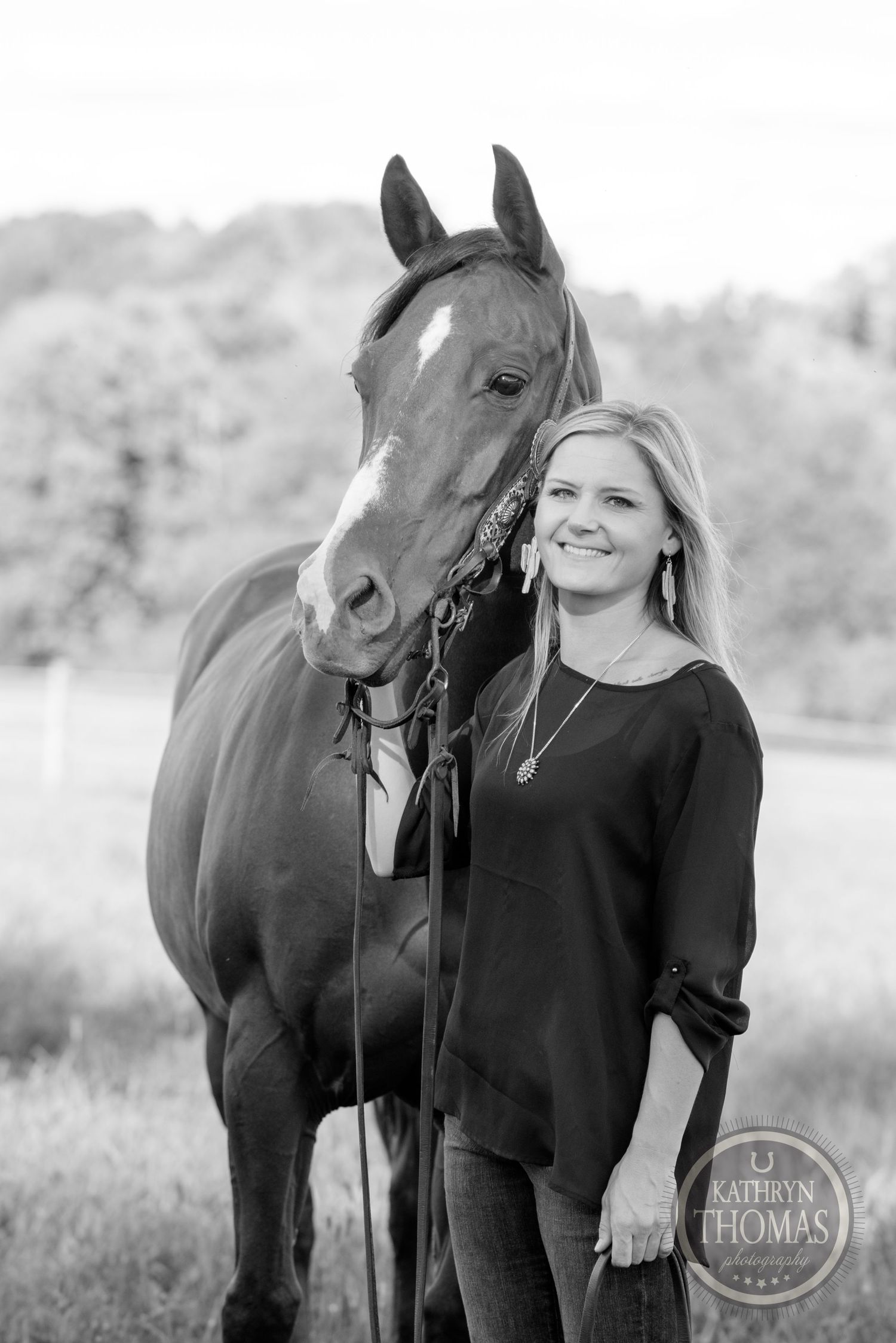 Black and white portrait of bay horse with someone in dark sweater outdoors.