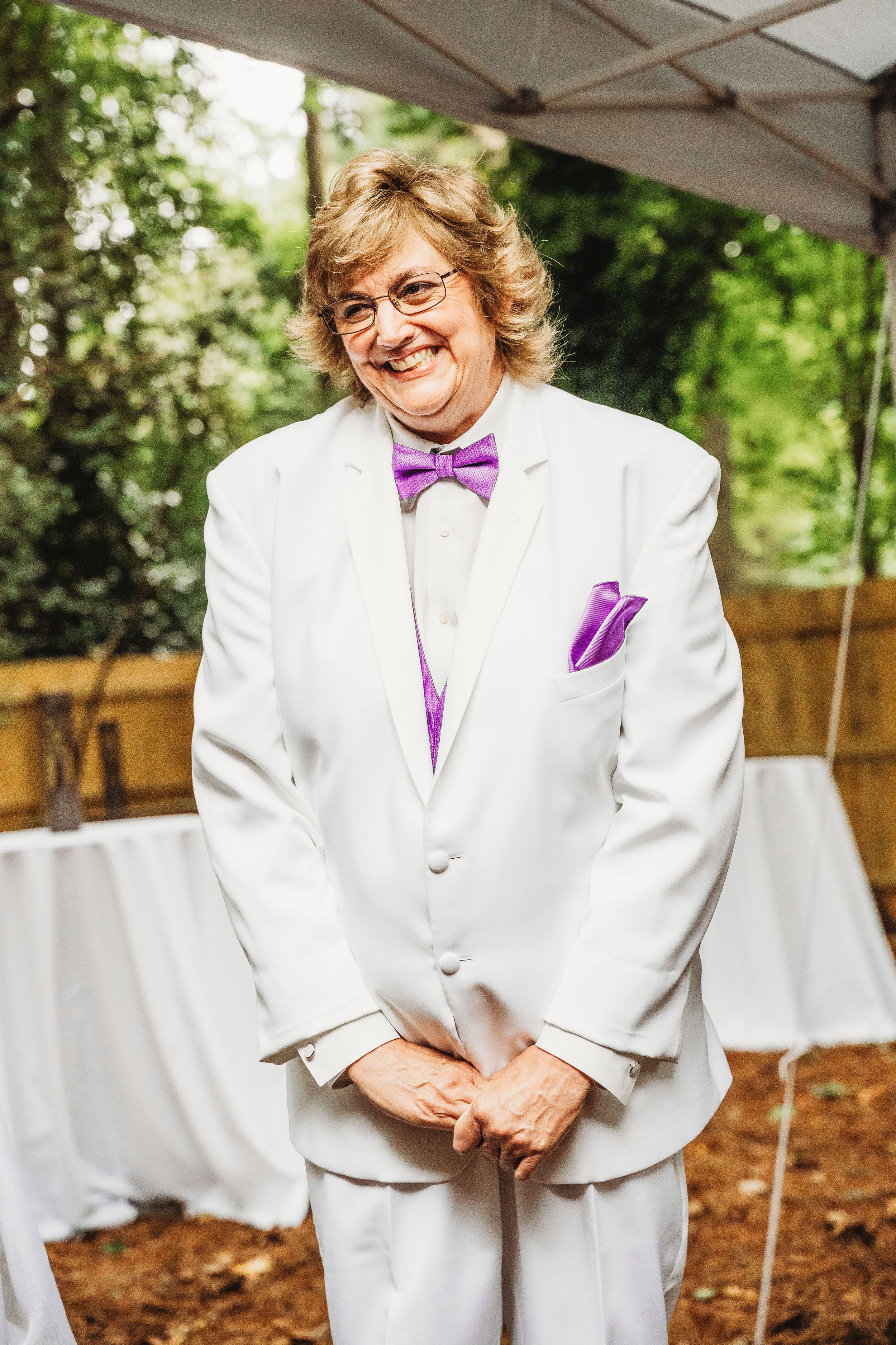 Bride waits for her bride at the alter while smiling uncontrollably