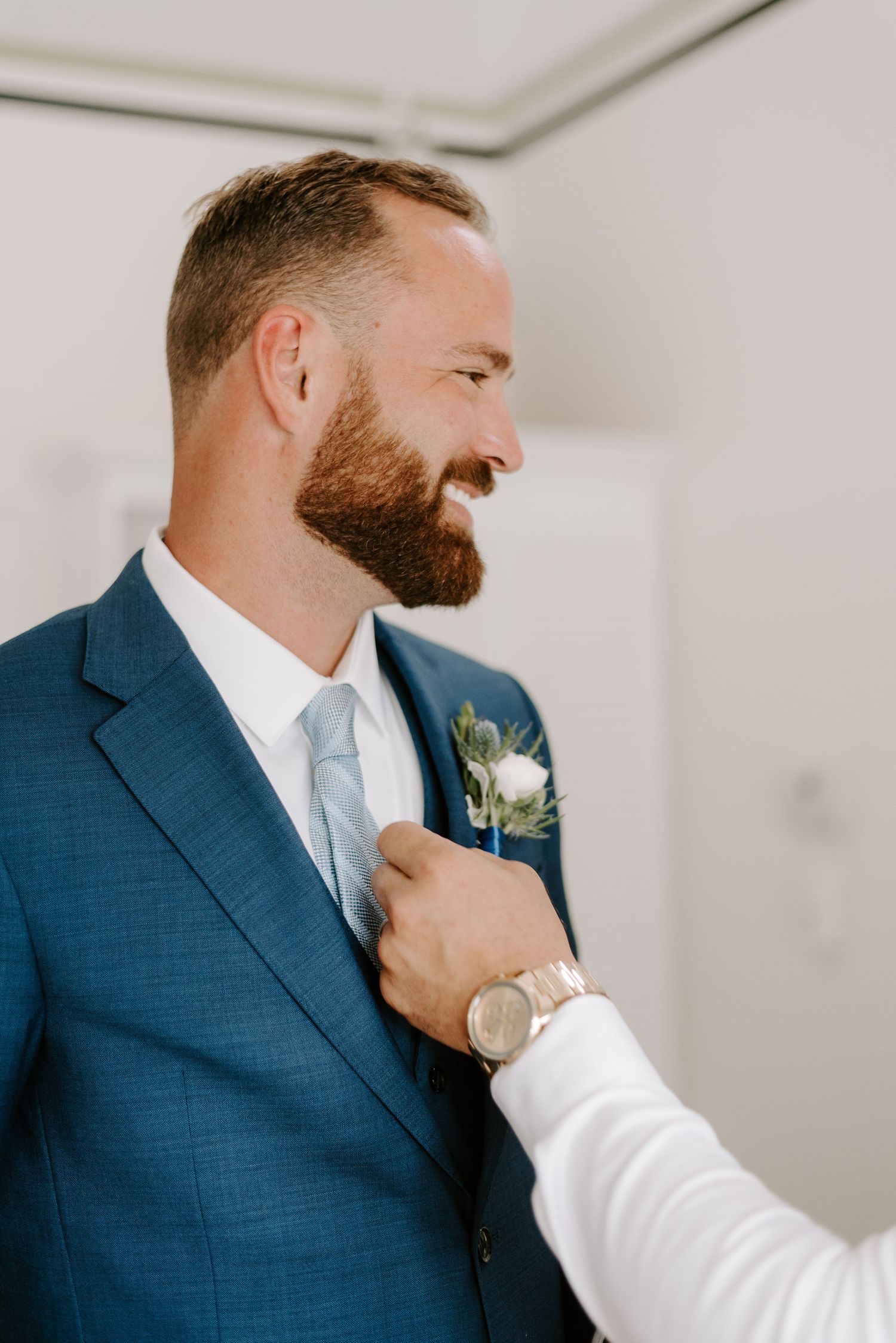Detail shots of a navy suit being adjusted and styled before a formal event.