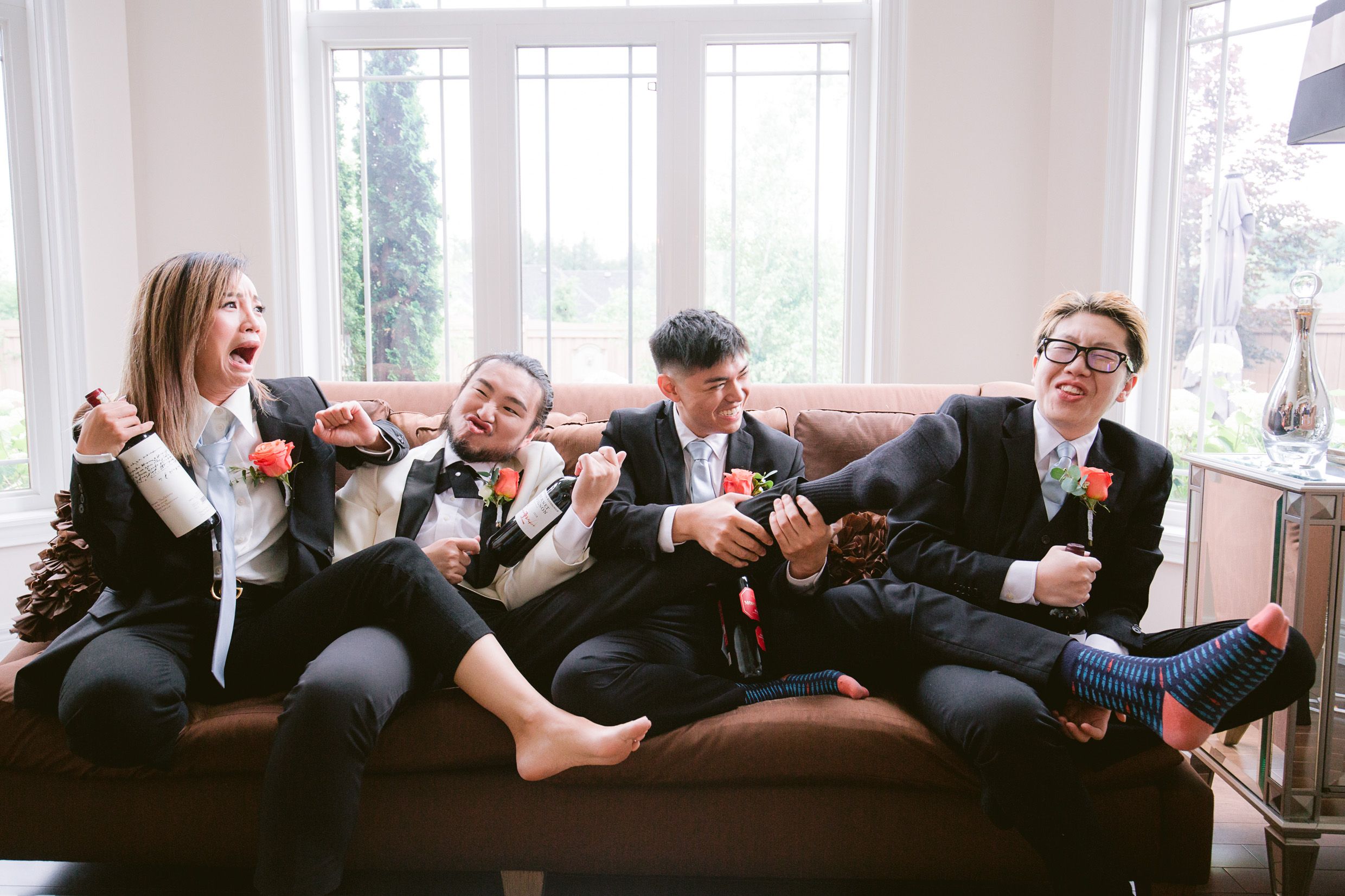 Groomsmen relaxing casually on couch in formal attire.