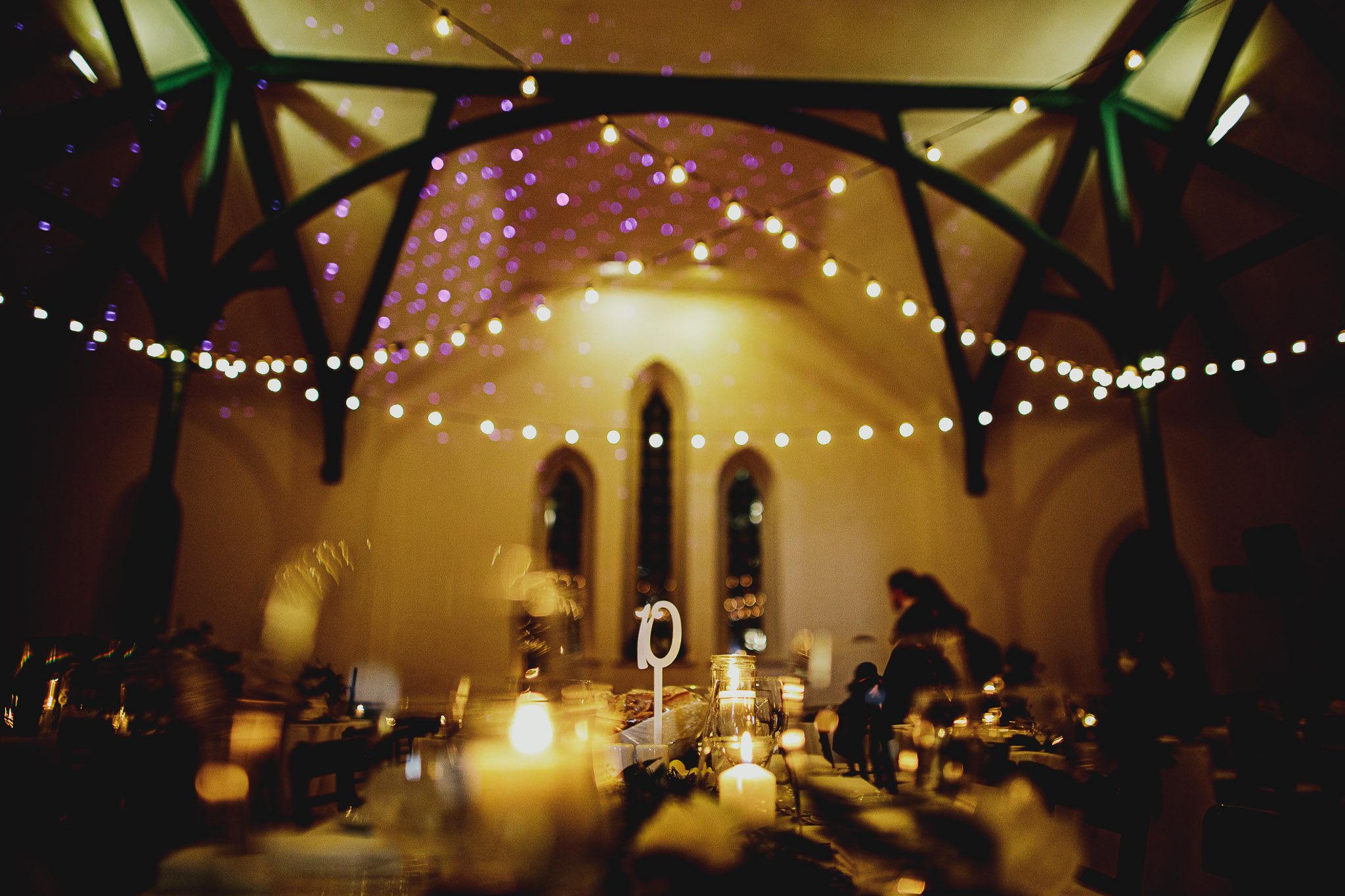 Romantic candlelit church reception with string lights creating dreamy atmosphere.