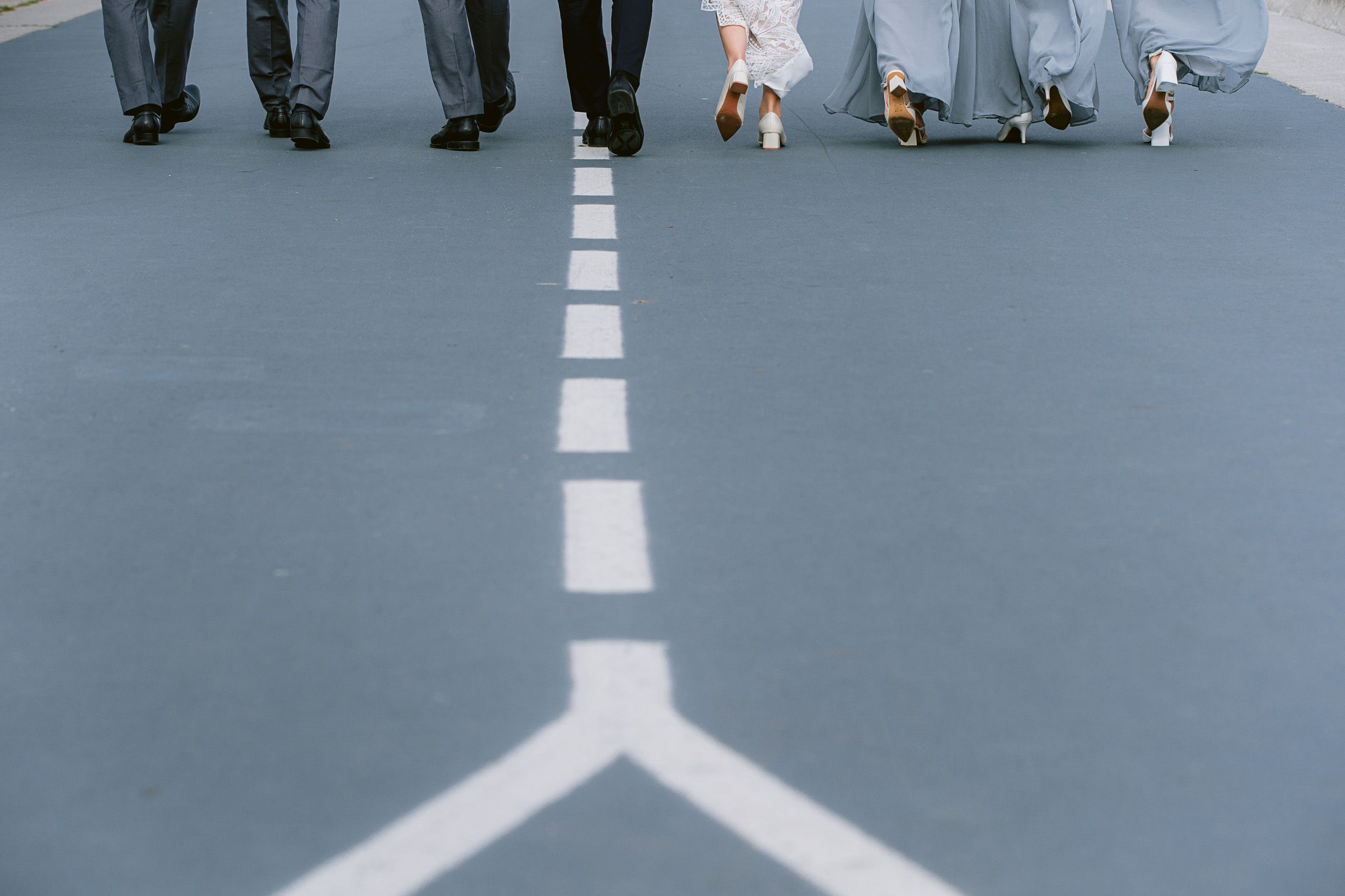 Feet and legs of people walking on a geometric floor pattern with white lines.