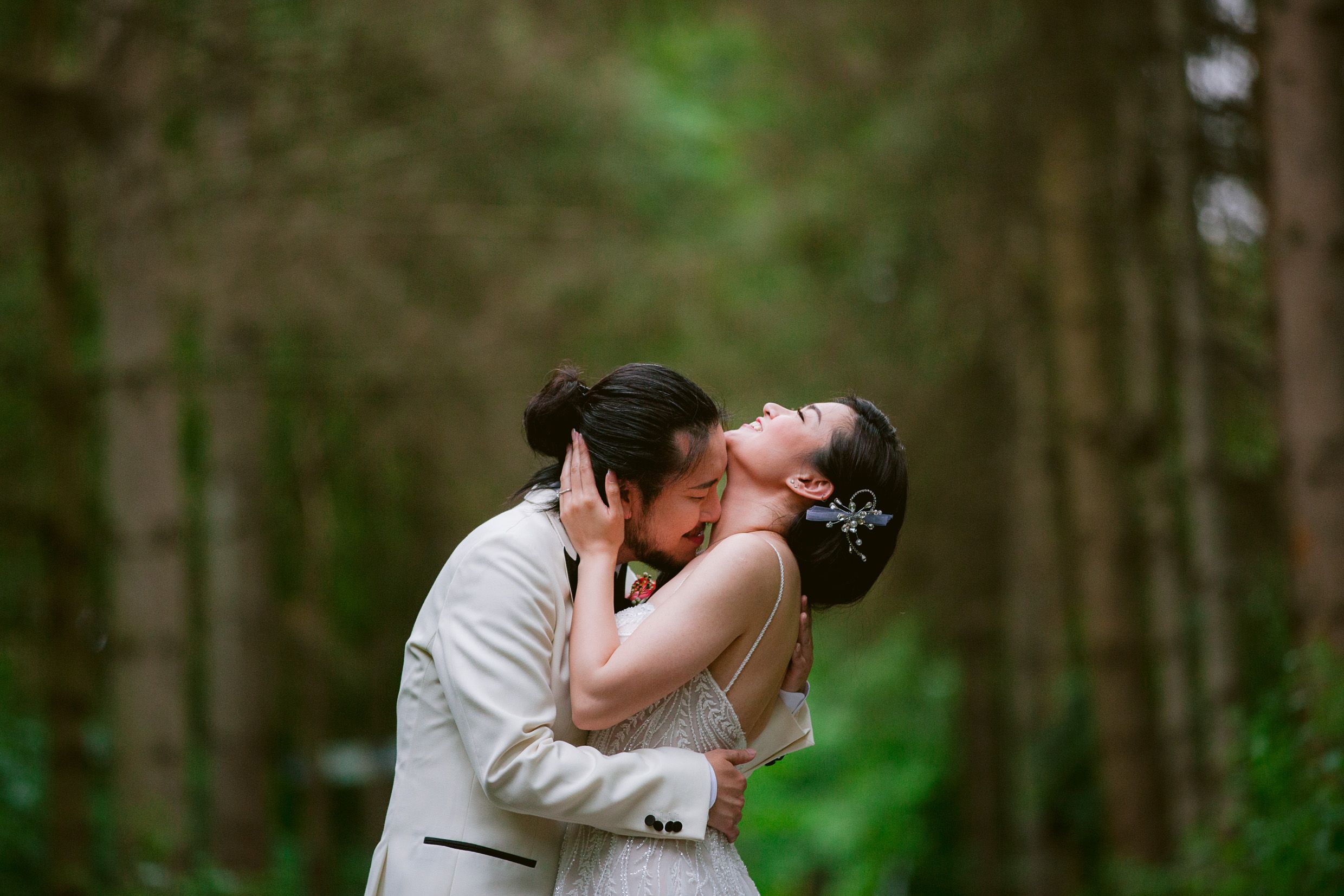 Romantic wedding moment captured in lush forest setting.